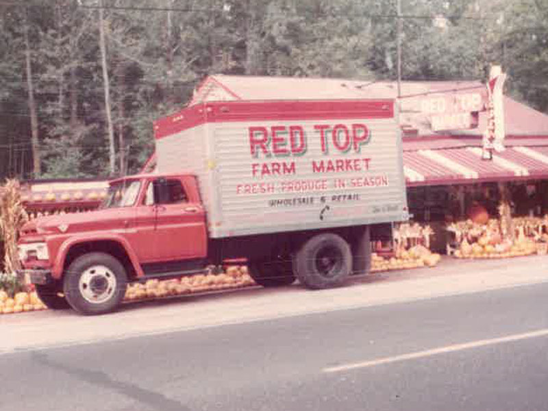 A historical sepia photo of a red and white truck that says Red Top Farm Market parked outside of the farm market.