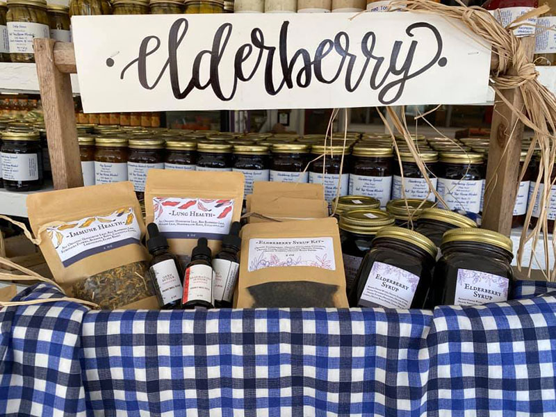 An assortment of elderberry products in bags, sprays, and jars underneath a sign that says Elderberry