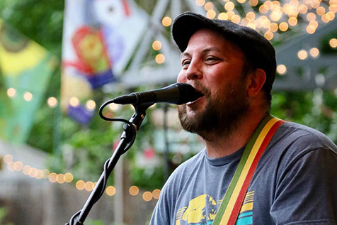 A man in a hat singing into a microphone at a local event held at Red Top Farm Market.