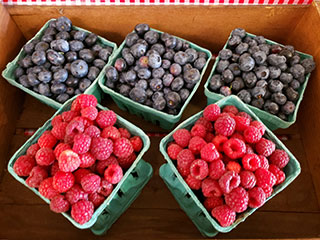 Cartons of raspberries and blueberries for sale.