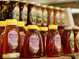 Rows of local bottles of honey for sale.